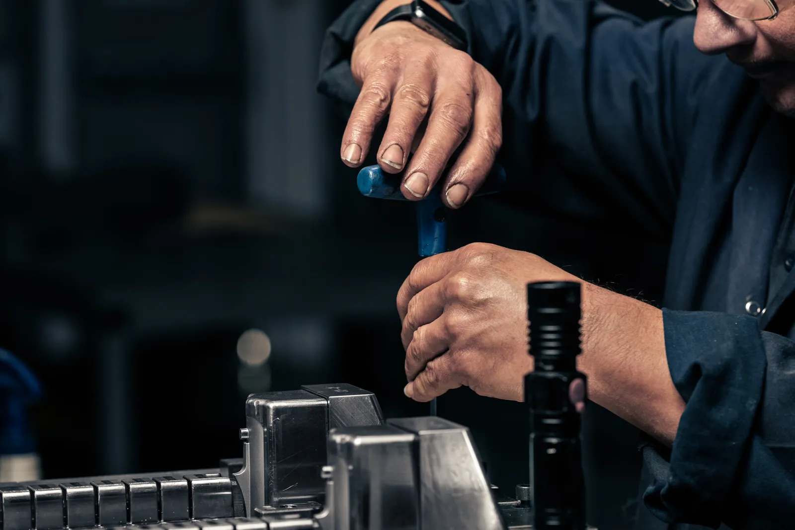 Close-up of a technician's hands adjusting a plastics mould tool