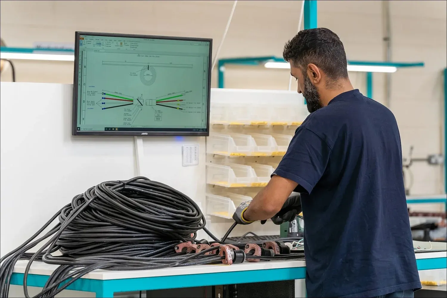 Manufacturing worker assembling a cable harness from a digital diagram