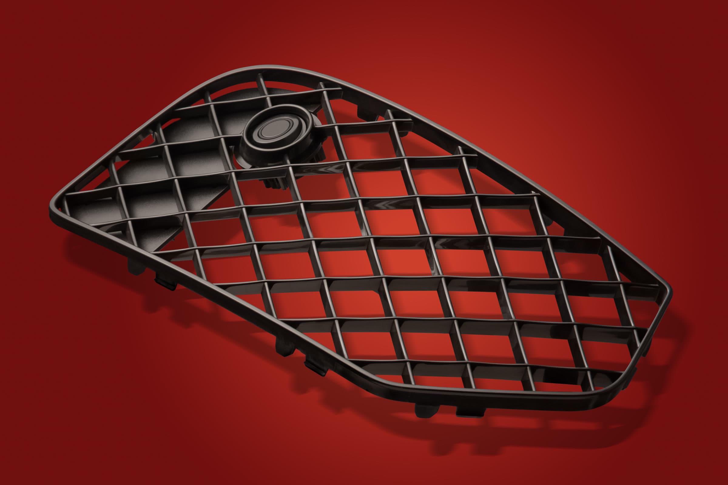 Black triangular moulded plastic grille photographed on a red studio background