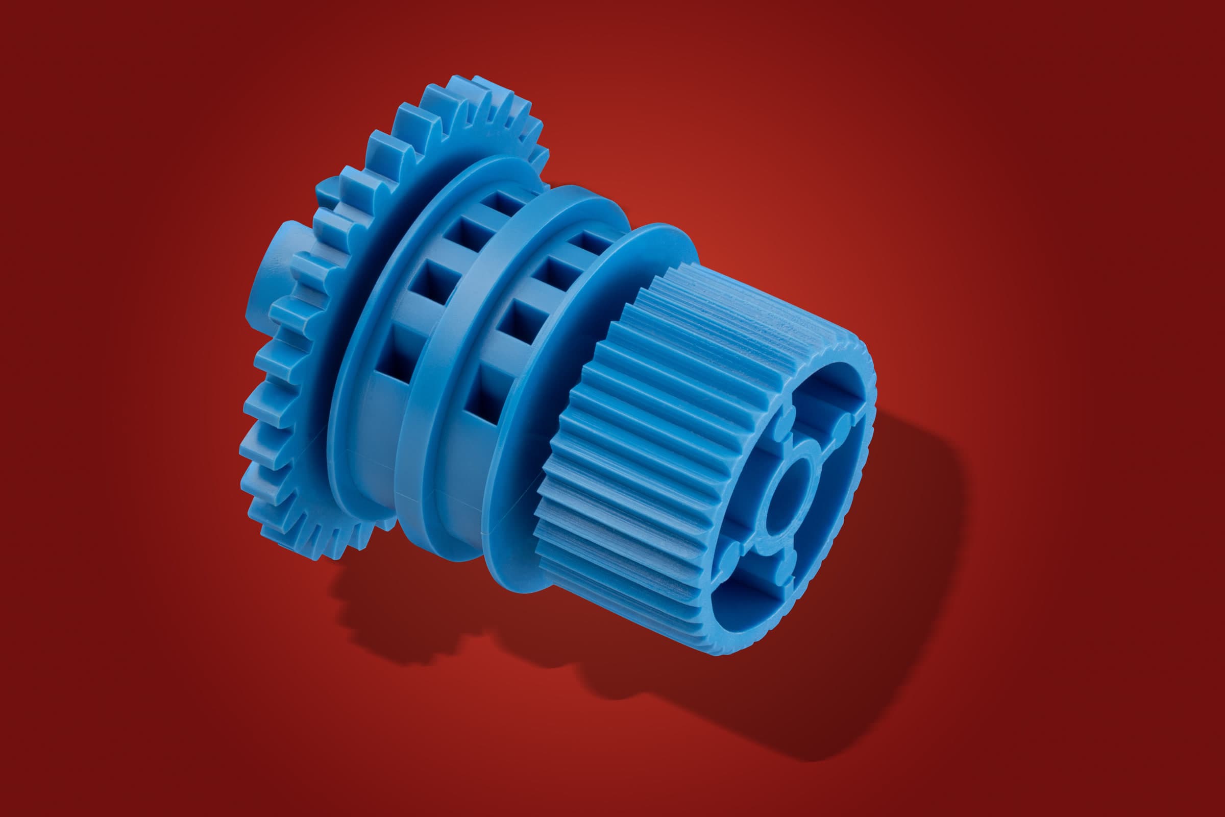 Blue geared plastic component photographed on a red studio background