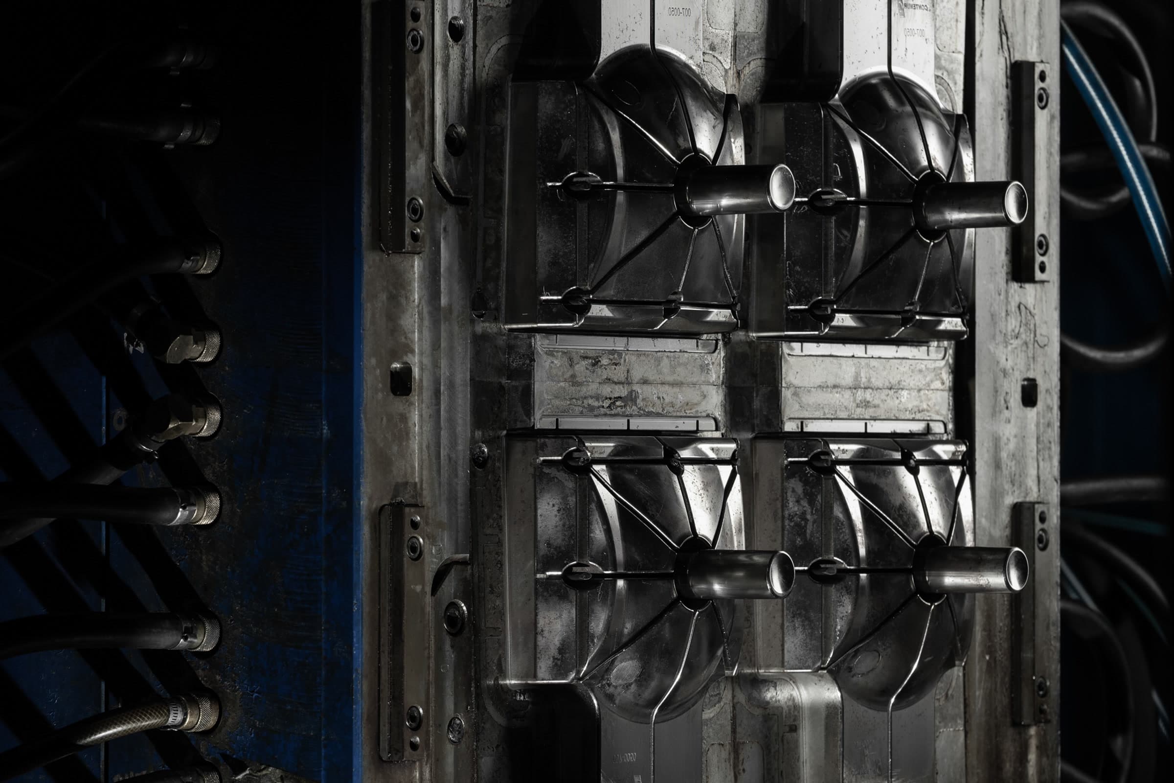 Dark close-up inside an open industrial moulding machine