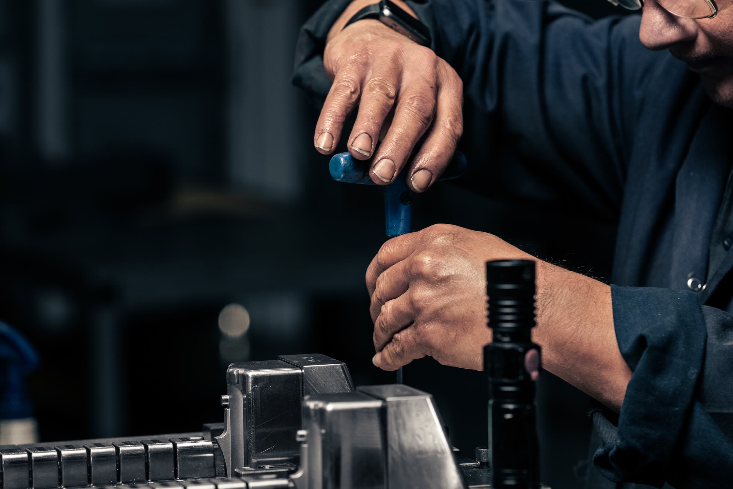 Close-up of a technician's hands adjusting a plastics mould tool