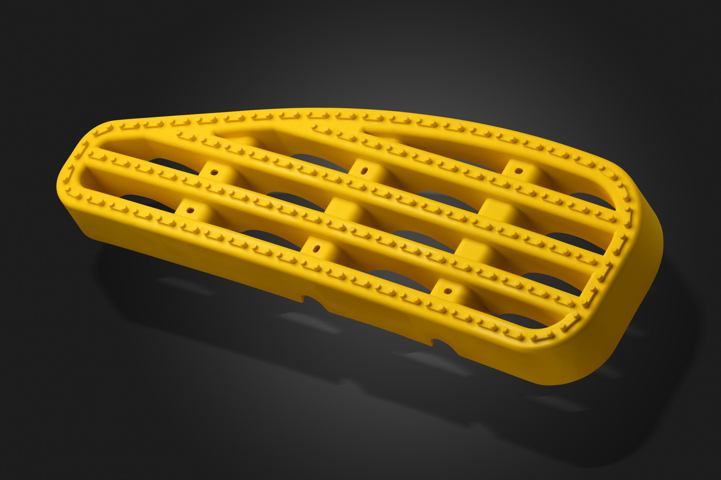 Yellow moulded plastic component photographed on a dark studio background