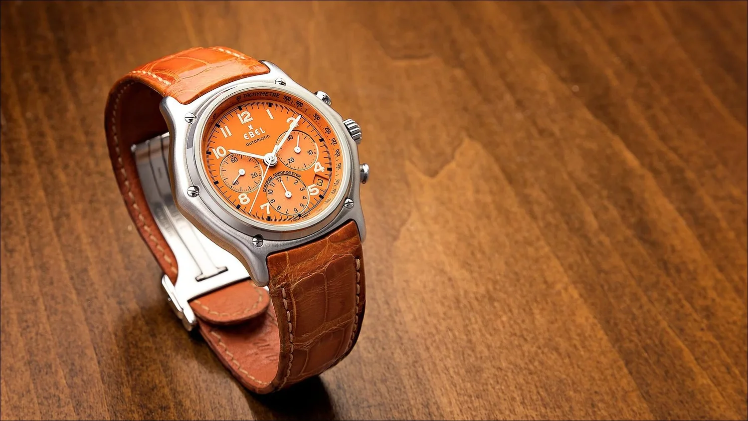 Ebel chronograph watch orange dial alligator strap wood table