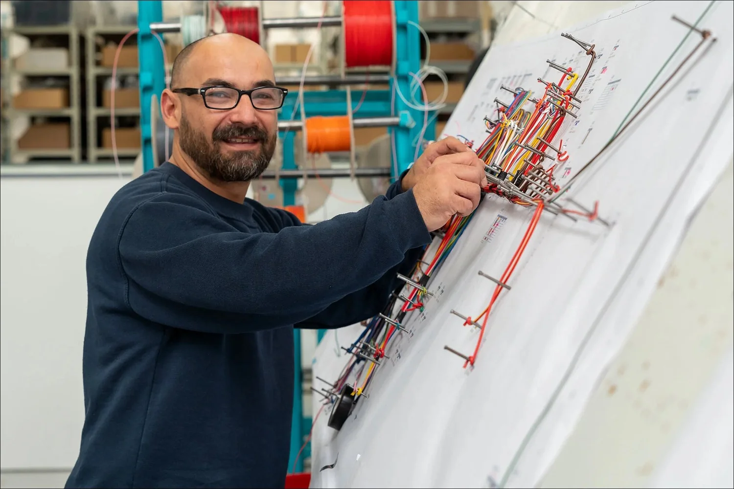 Bearded technician wiring harness board manufacturing