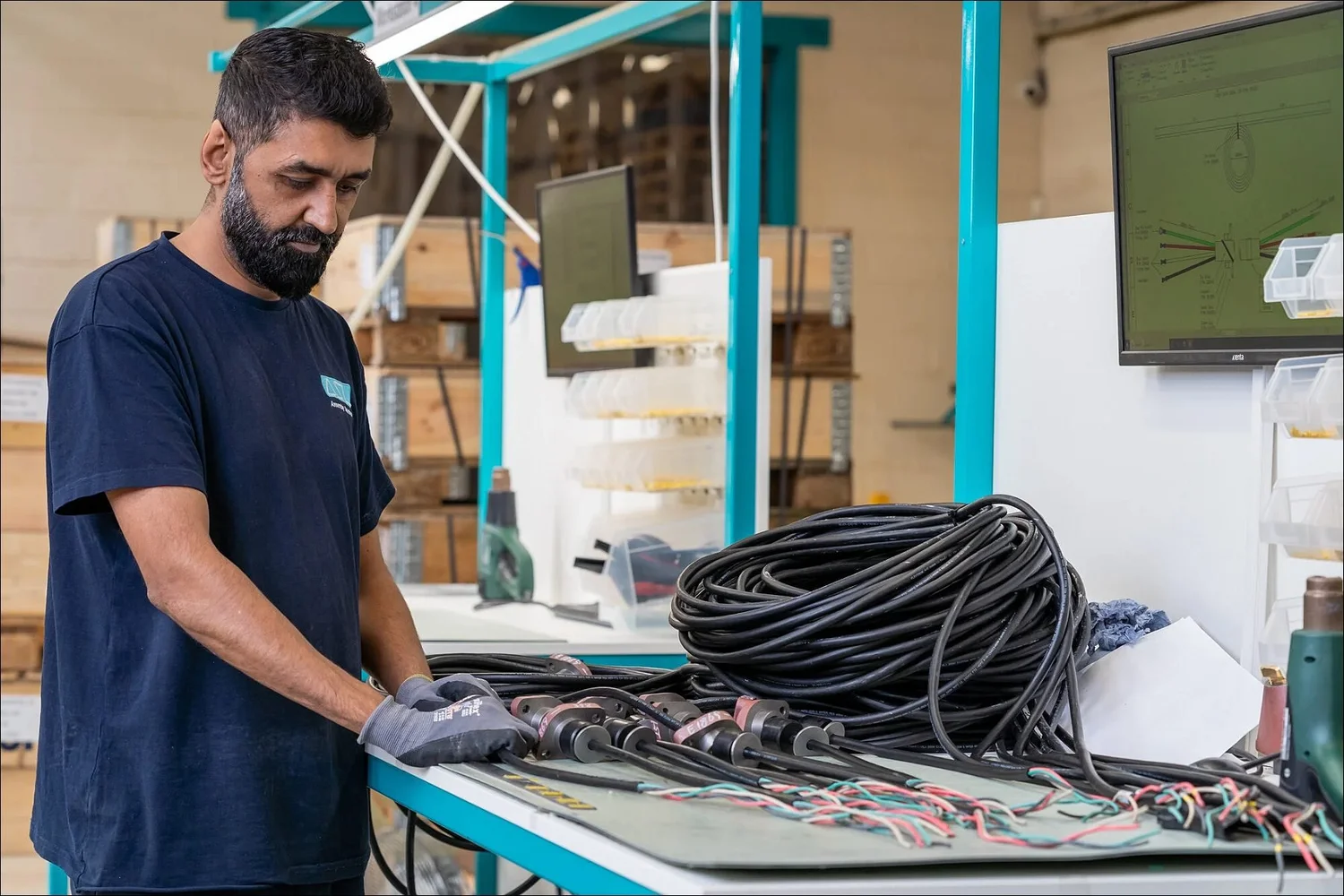 Bearded worker handling heavy duty cables in manufacturing image