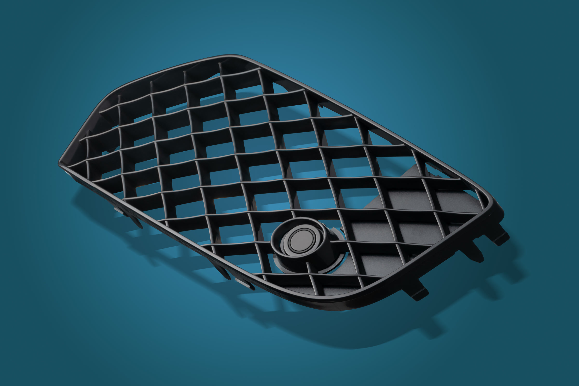 Black triangular moulded plastic grille photographed on a blue studio background