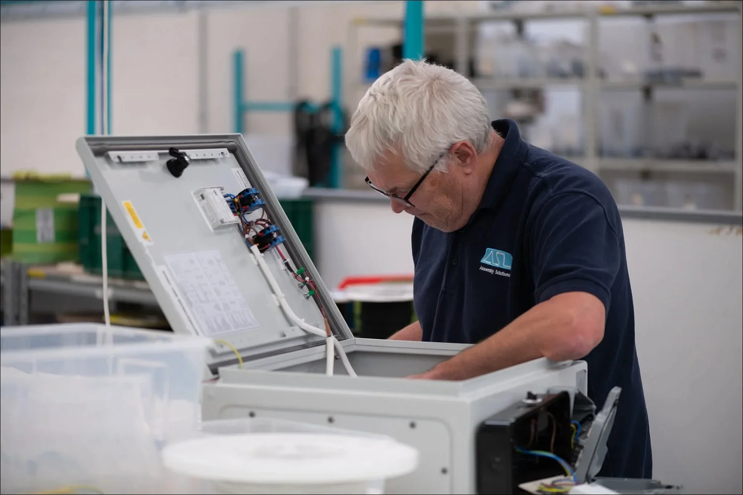 Senior technician assembles open electrical panel