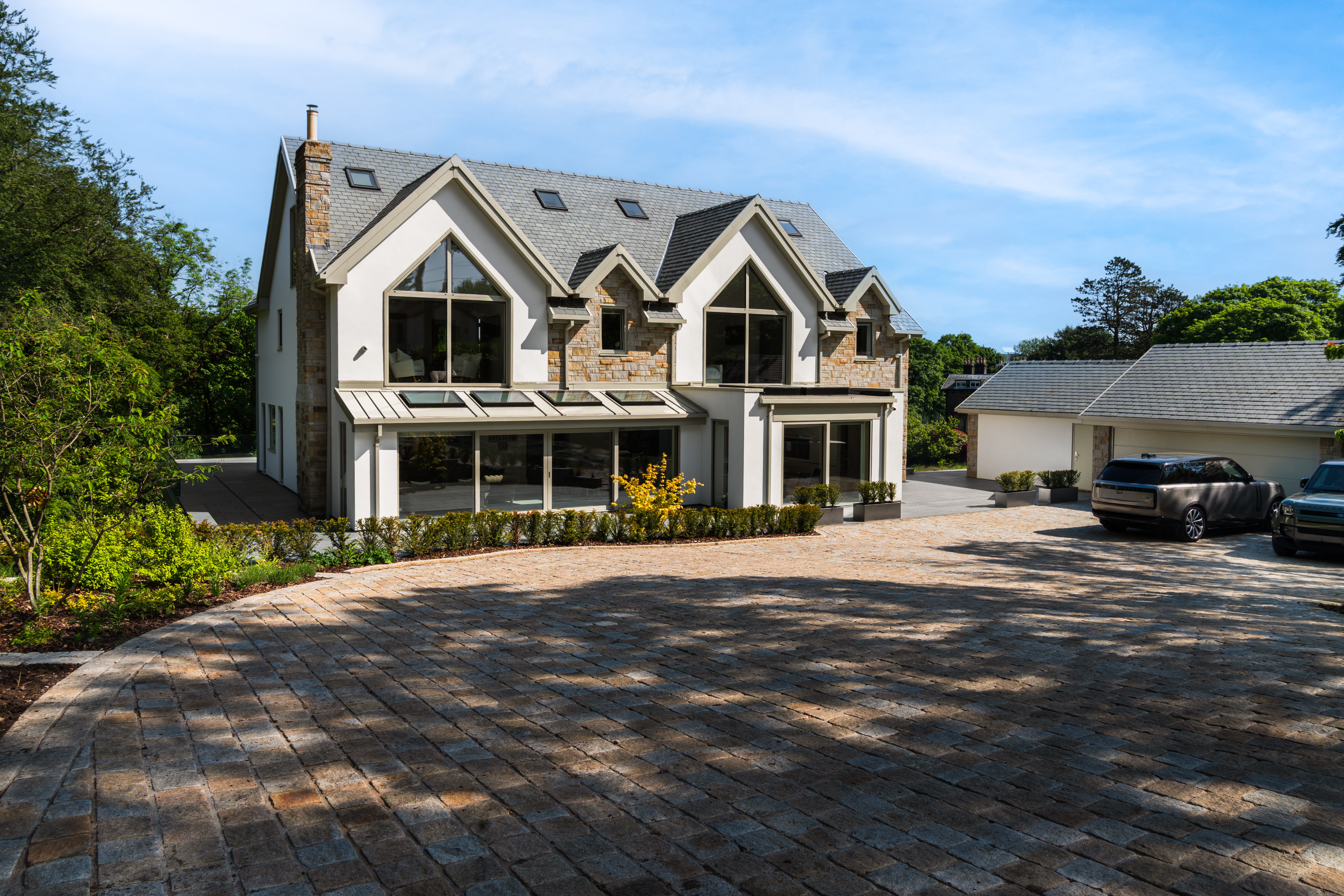 Exterior of a contemporary stone and render detached home with gabled windows and a gravel driveway