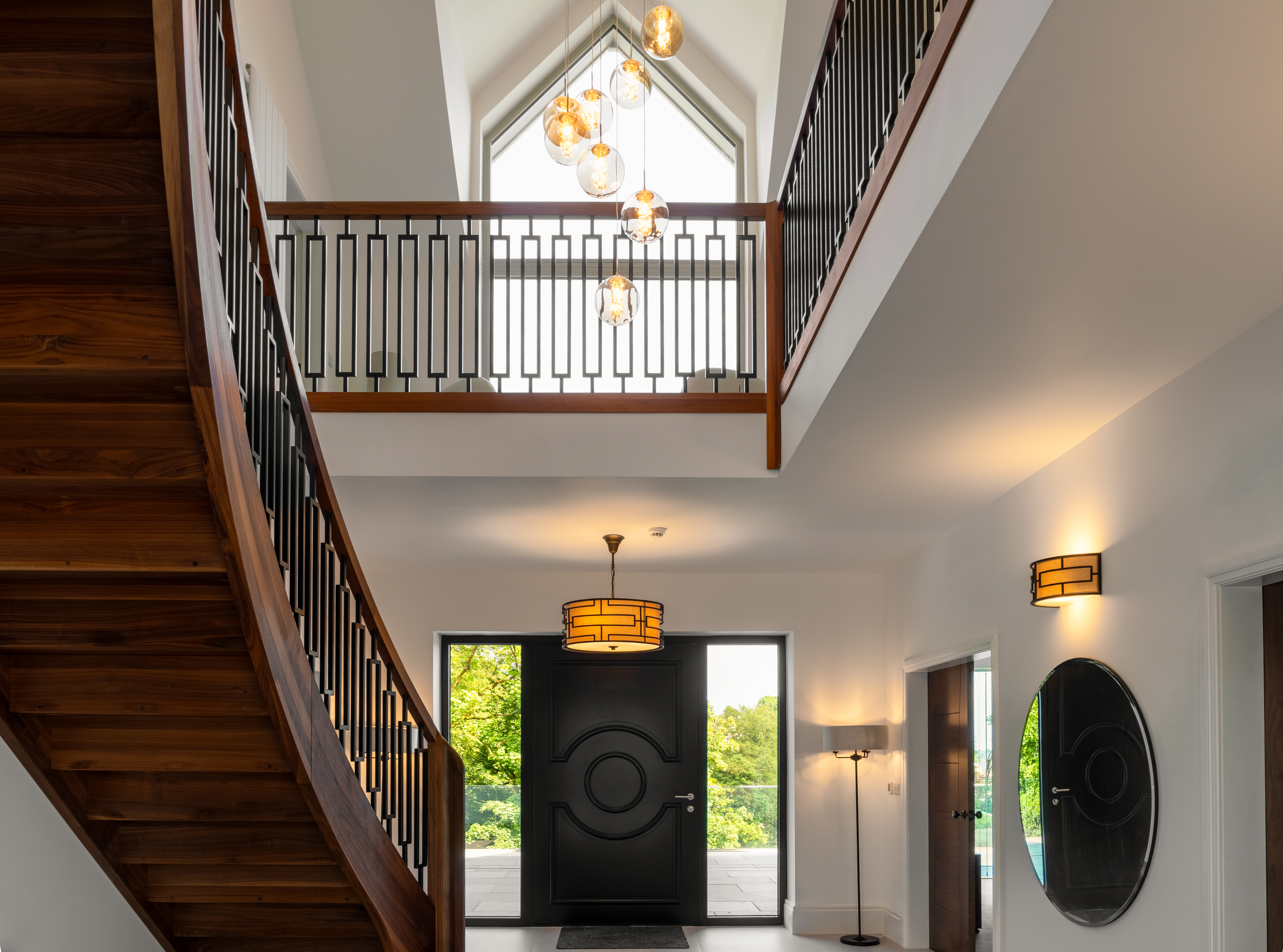 Double-height entrance hall with a curved oak staircase, galleried landing and arched window